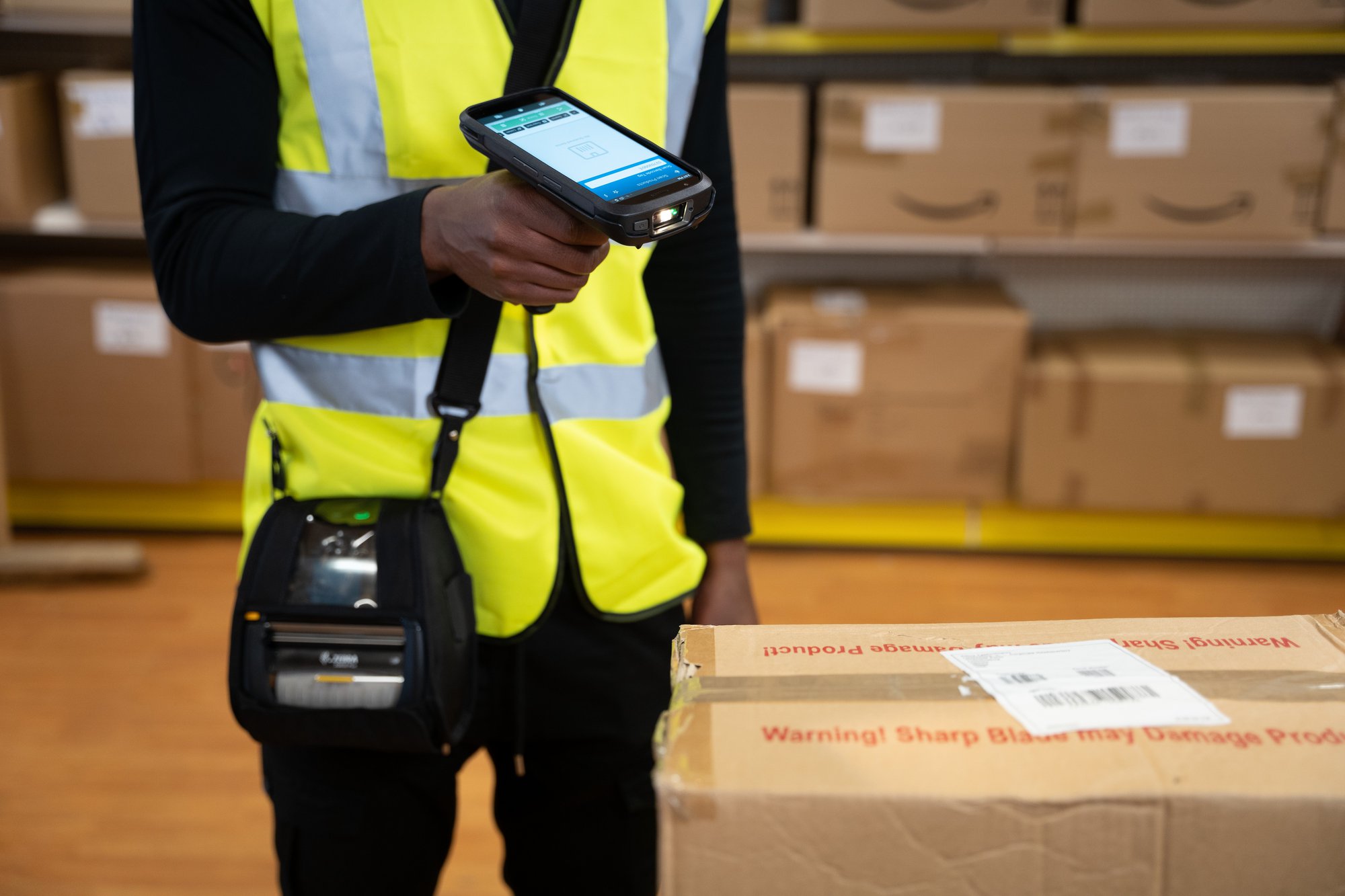 Warehouse worker using a Zebra TechnologiesTC22 that has been through the Windows CE to Android migration process to scan a box