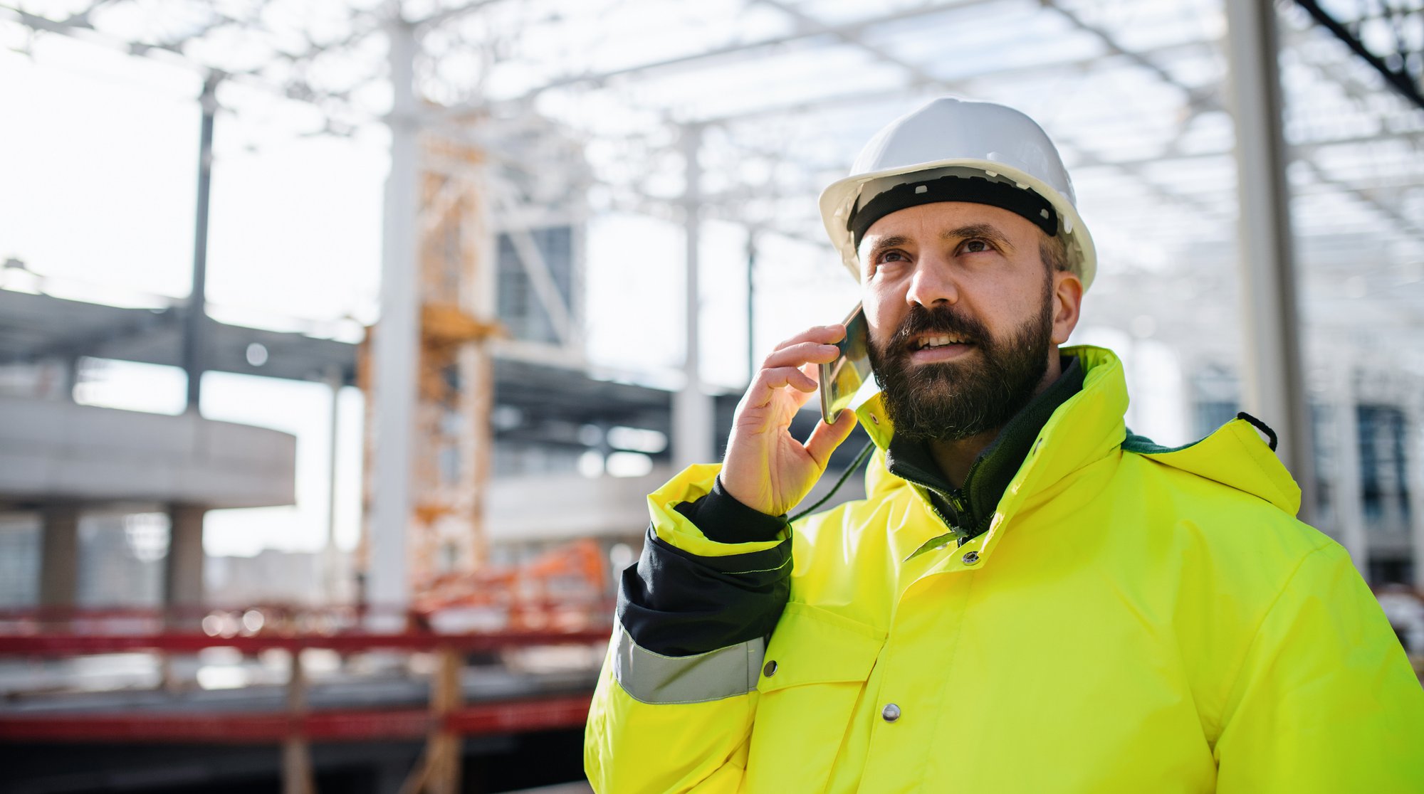 Man in high-vis and hard hat using a tough phone