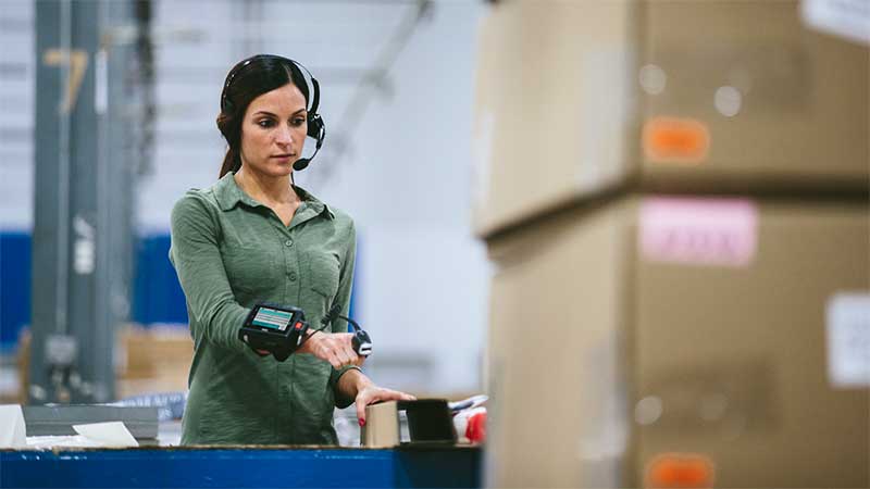 Warehouse worker scanning boxes with Zebra scanners following systems integration