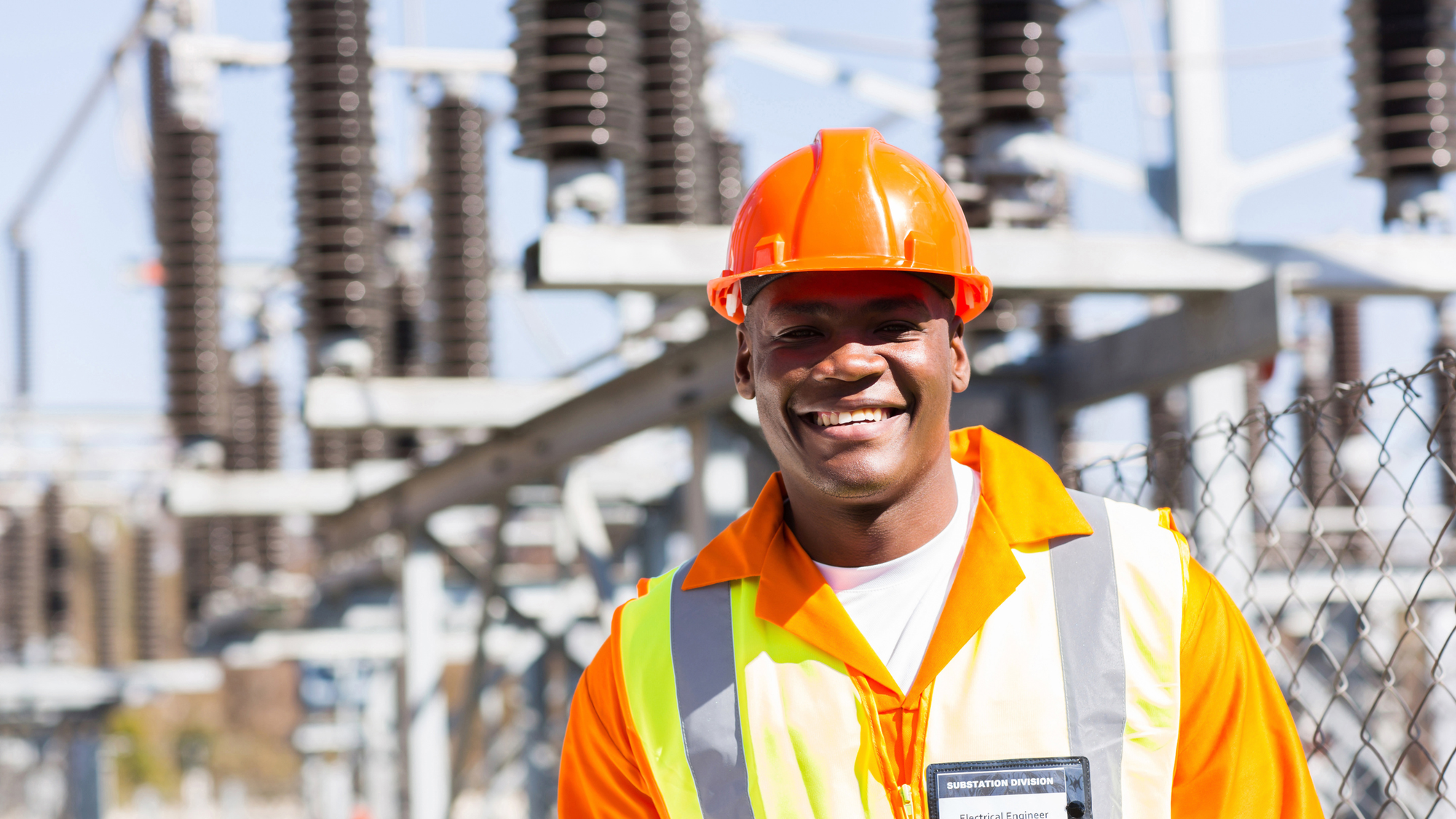 Electrical Engineer In Front Of Pylons Smiling As Has A New Enterprise Tablet