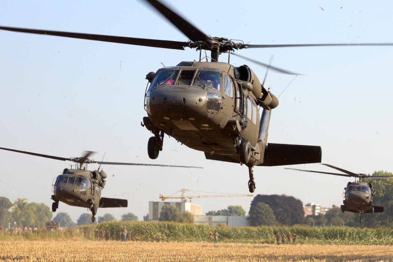 Military helicopters landing in a field