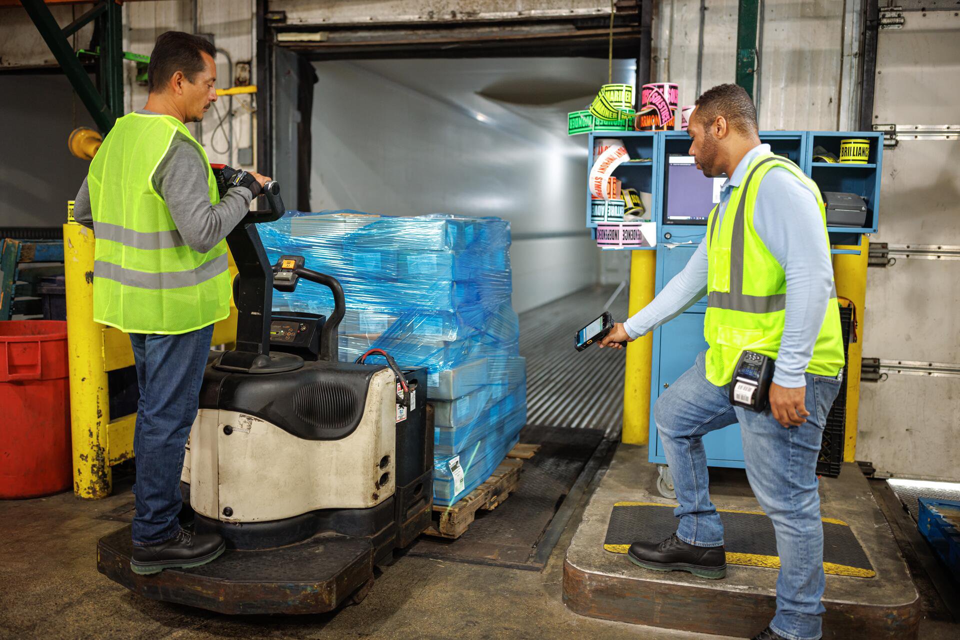 2 warehouse workers using a Zebra Technologies ZQ610 rugged mobile printer to print labels for a pallet of boxes