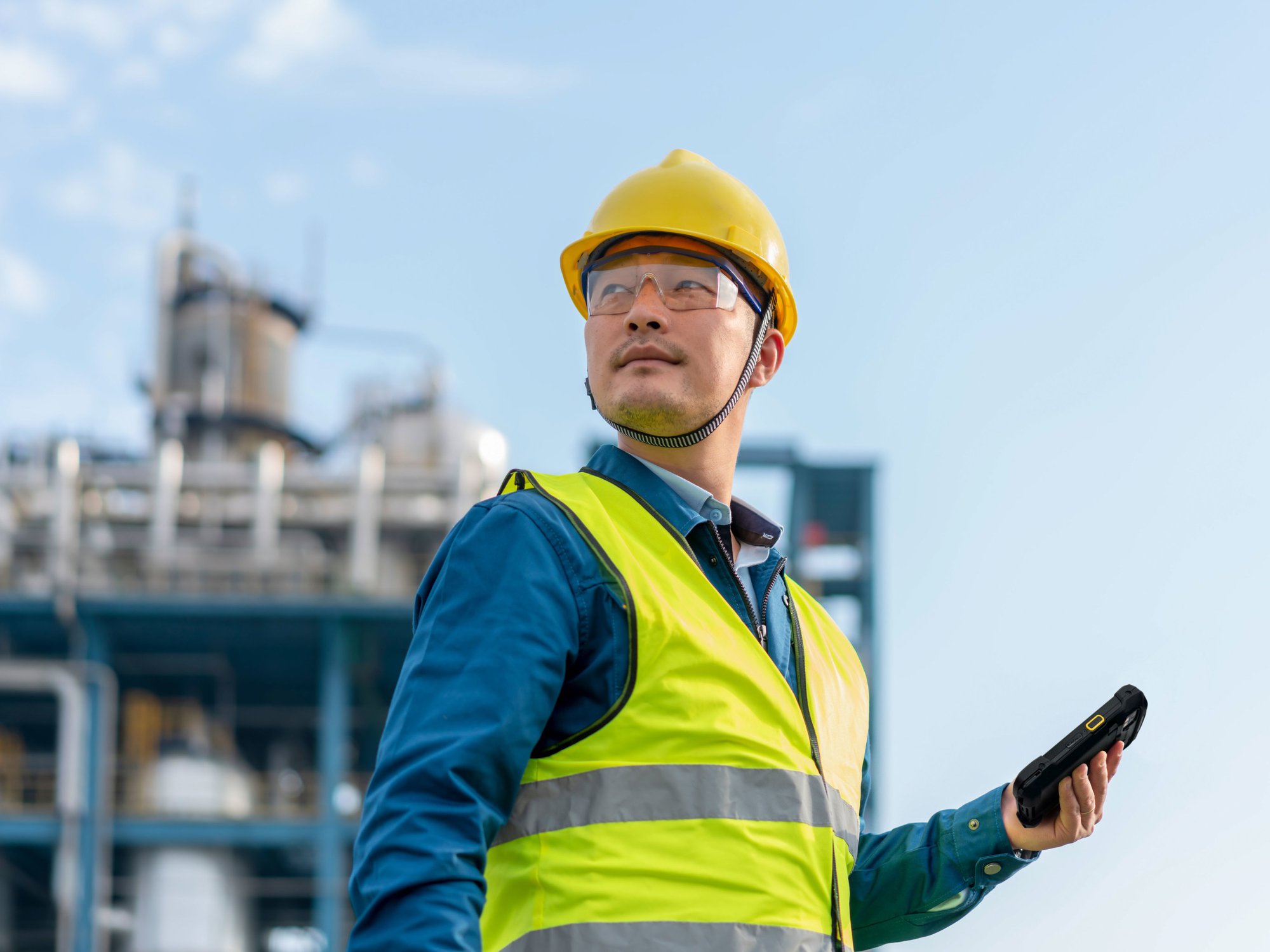 An engineer reviews a Zebra handheld mobile computer outside of an industrial plant