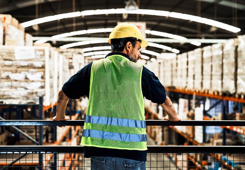 Worker standing on an elevated walkway looking at the warehouse floor.